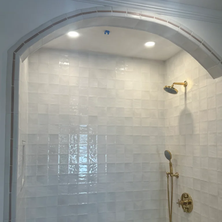 Fancy shower with a bow and square tiles in the wall.