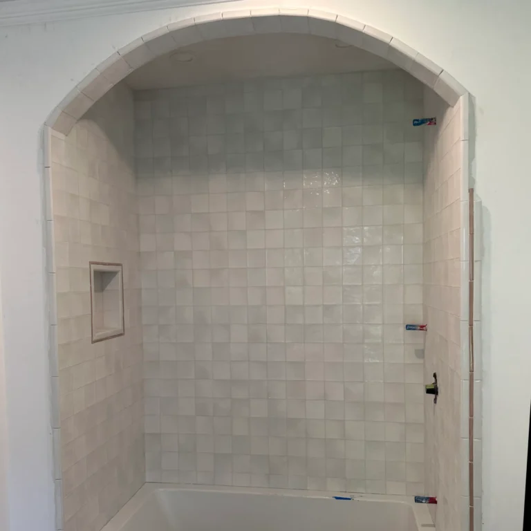 Fancy shower with a bow and square tiles in the wall.