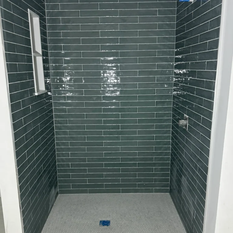 Shower with green rectangular wide tiles in a brick pattern.