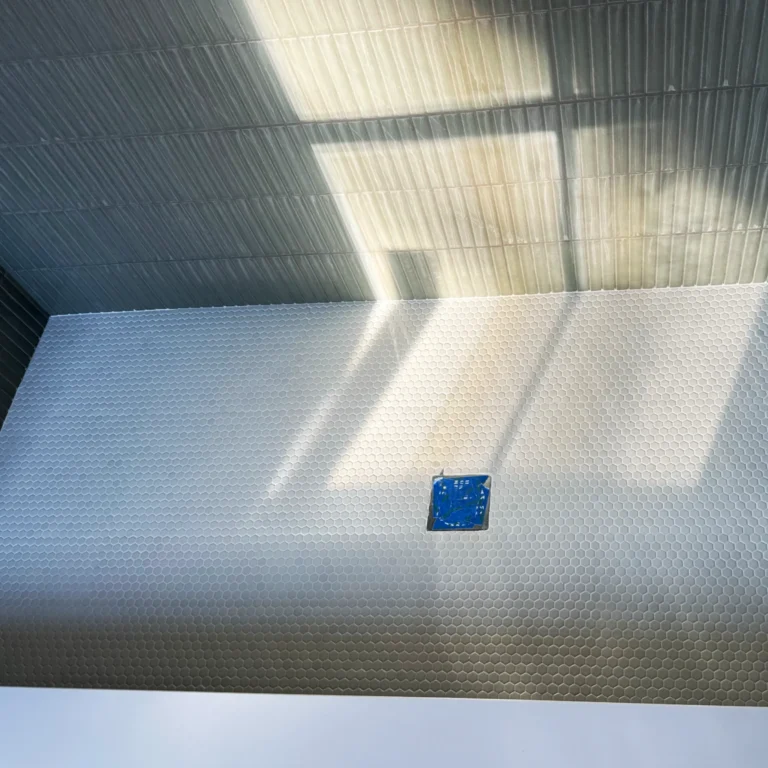 A shower with a small circular tile in the floor.