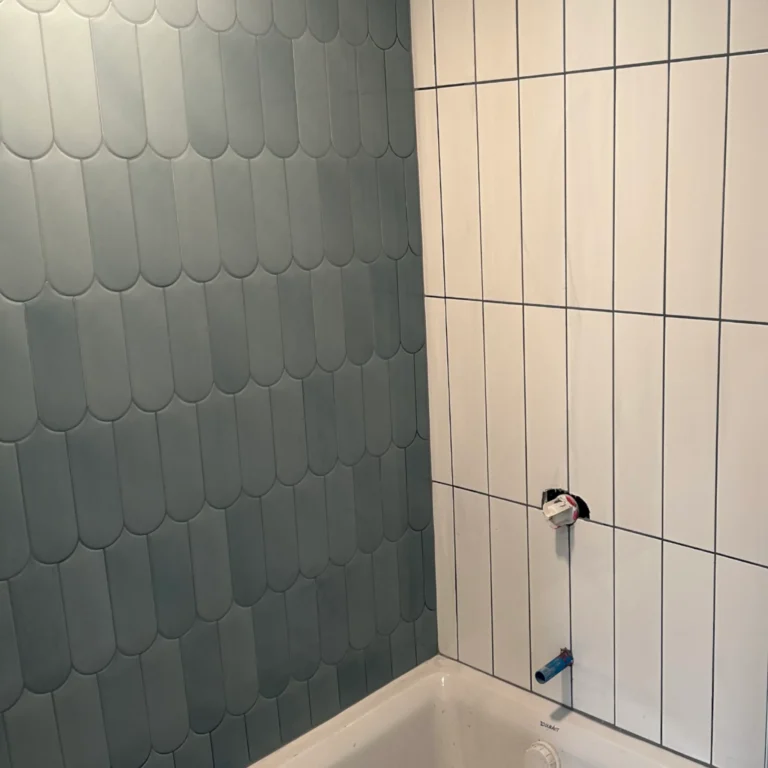 FIsh scale green tile and white rectangular tile in a parallel pattern in a shower.