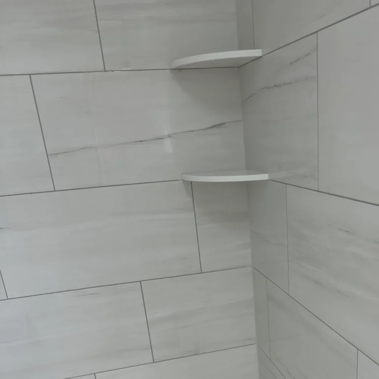 Two shelves in a shower with tiles.