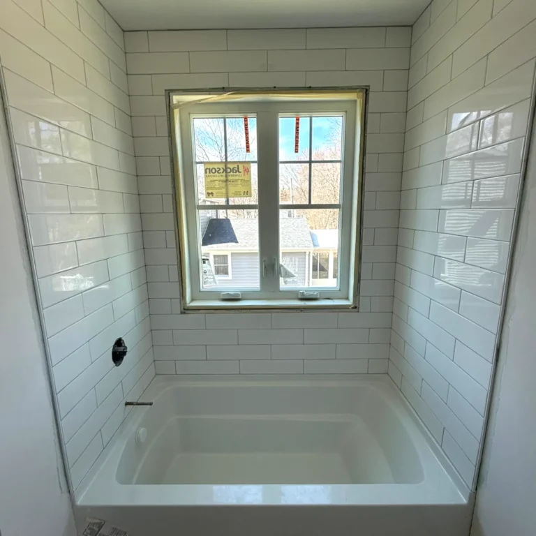 Small shower with white tiles in a brick pattern.