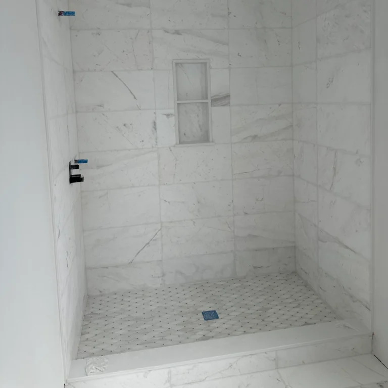Shower with white stone tiles in a parallel pattern.