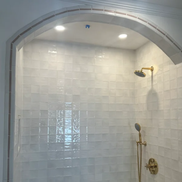 Fancy shower with a bow and square tiles in the wall.