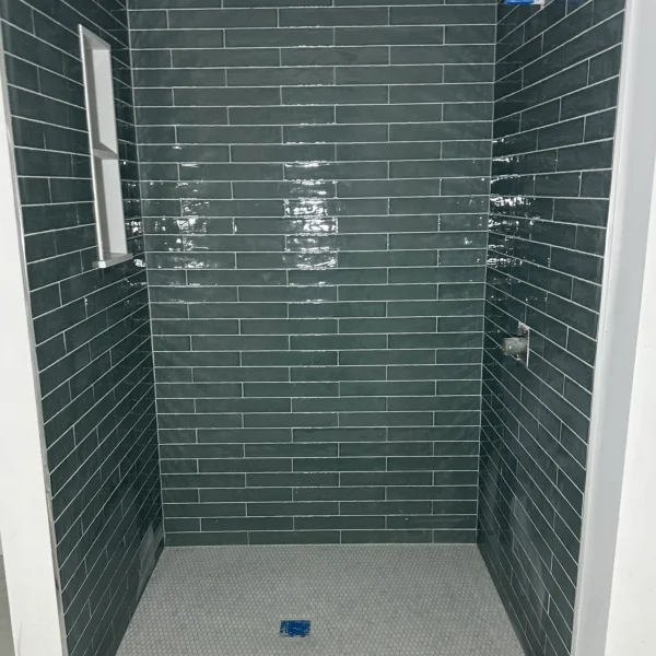 Shower with green rectangular wide tiles in a brick pattern.