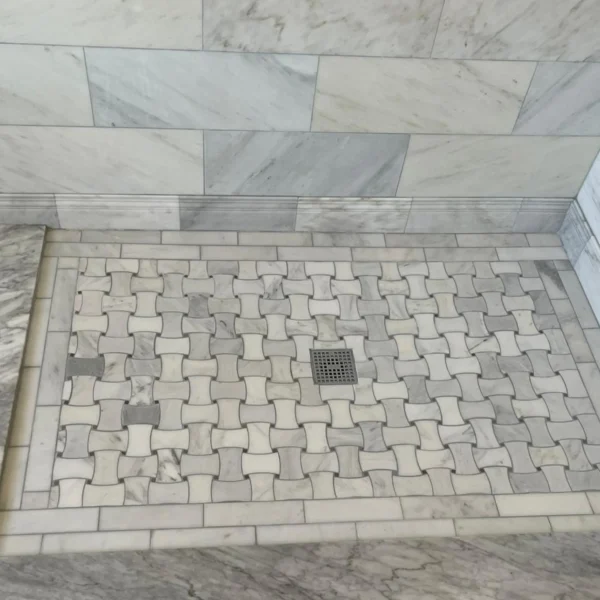 Fancy shower with a mosaic floor and brick pattern in the wall.
